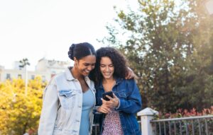 African-American friends using a smartphone in the park.